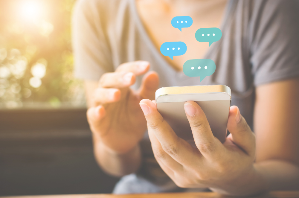 Image of a person holding a phone with chat bubbles above it